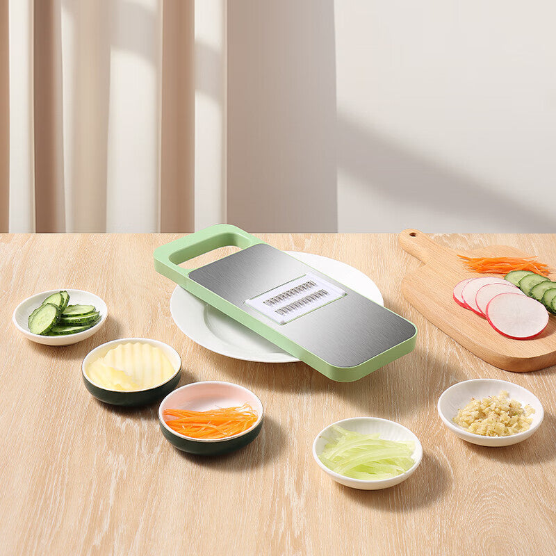 Vegetable chopper on a wooden table with sliced vegetables in small bowls.