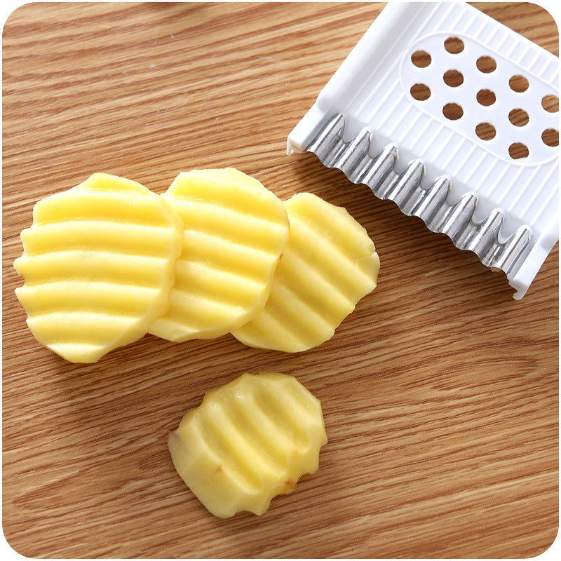 Waved potato slices on a wooden surface with a potato peeler.