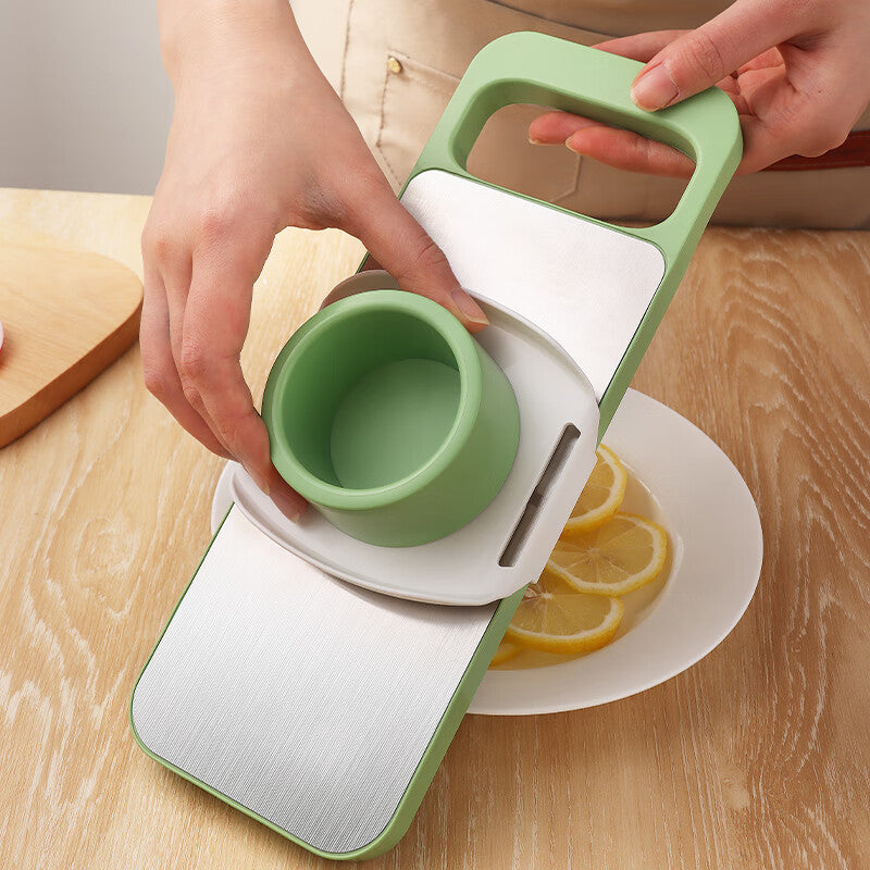 Green and white kitchen tool being used on a wooden surface with lemons.