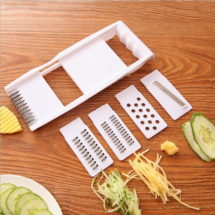 Multifunctional vegetable slicer with different blades on a wooden surface, showing sliced vegetables.